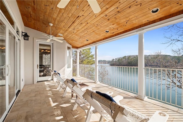 sunroom featuring vaulted ceiling, wooden ceiling, ceiling fan, and a water view