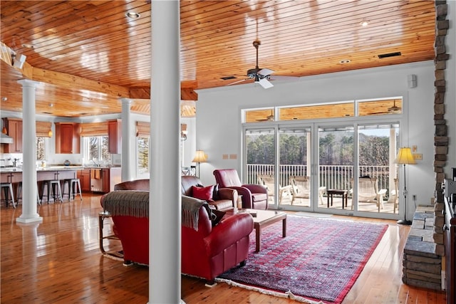 living room with wood ceiling, light hardwood / wood-style floors, a healthy amount of sunlight, and ornate columns