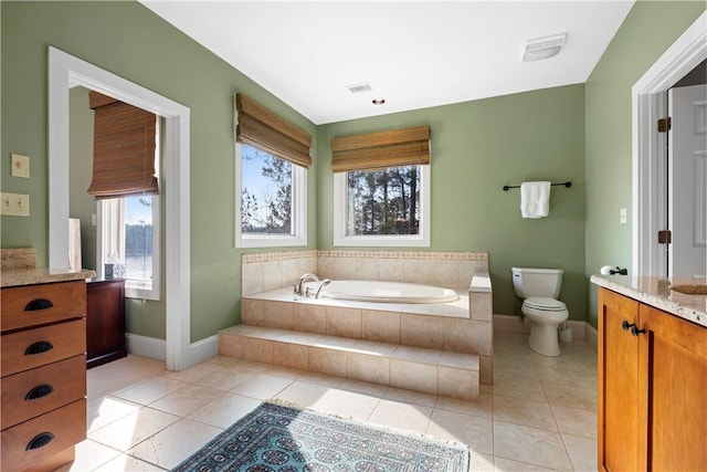 bathroom with vanity, tile patterned flooring, tiled bath, and toilet