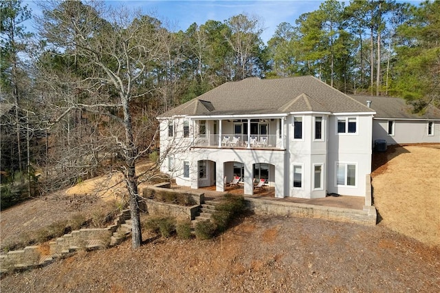 view of front of property featuring a patio, central AC, and a balcony