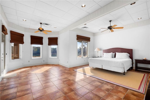 tiled bedroom with ceiling fan and a paneled ceiling