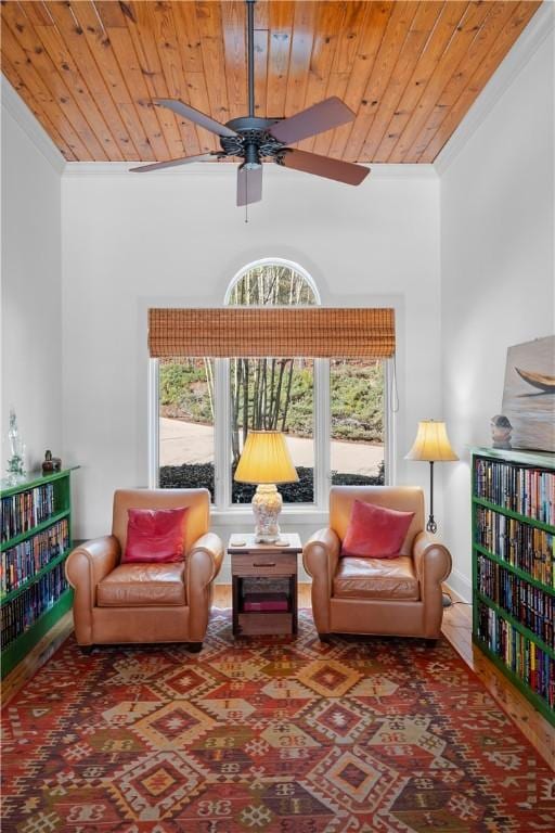 living area with wood ceiling, ceiling fan, and ornamental molding