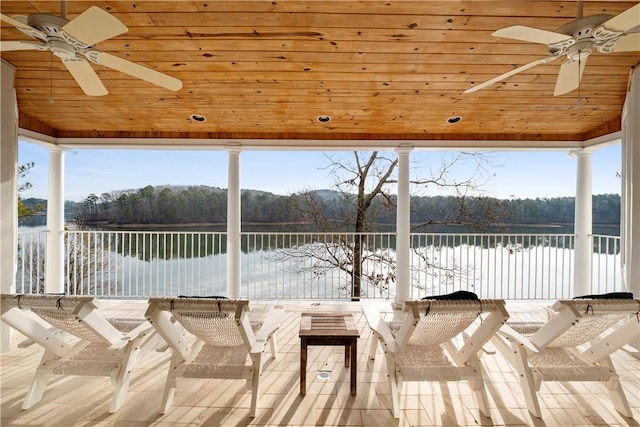 exterior space with a water view, ceiling fan, and an outdoor bar