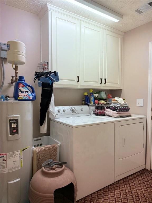 clothes washing area with washing machine and dryer, a textured ceiling, visible vents, electric water heater, and cabinet space
