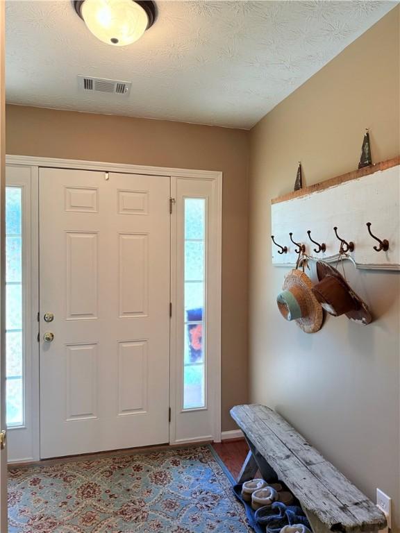 foyer entrance featuring baseboards, visible vents, and wood finished floors
