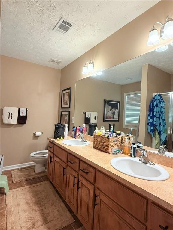 bathroom with double vanity, toilet, visible vents, and a sink