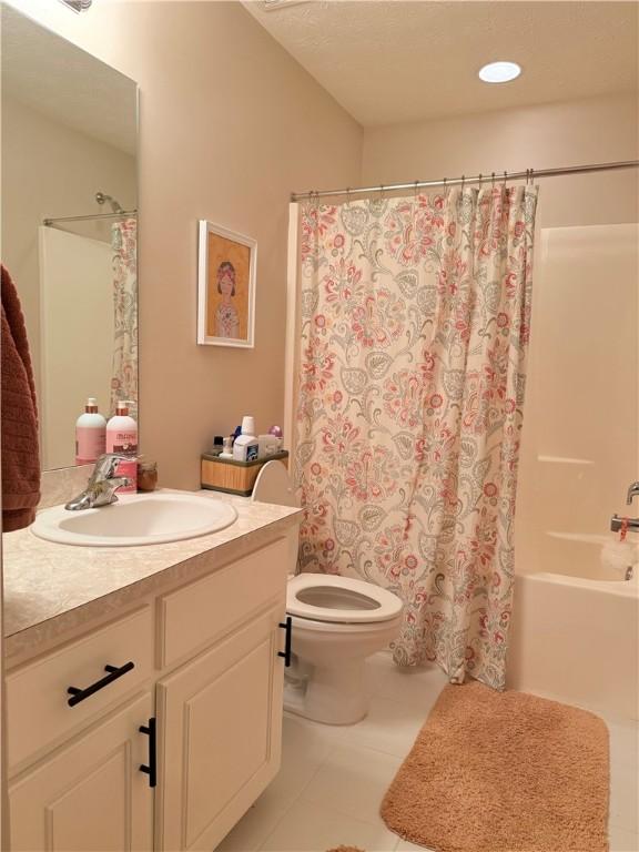 bathroom featuring toilet, tile patterned flooring, vanity, and shower / bathtub combination with curtain