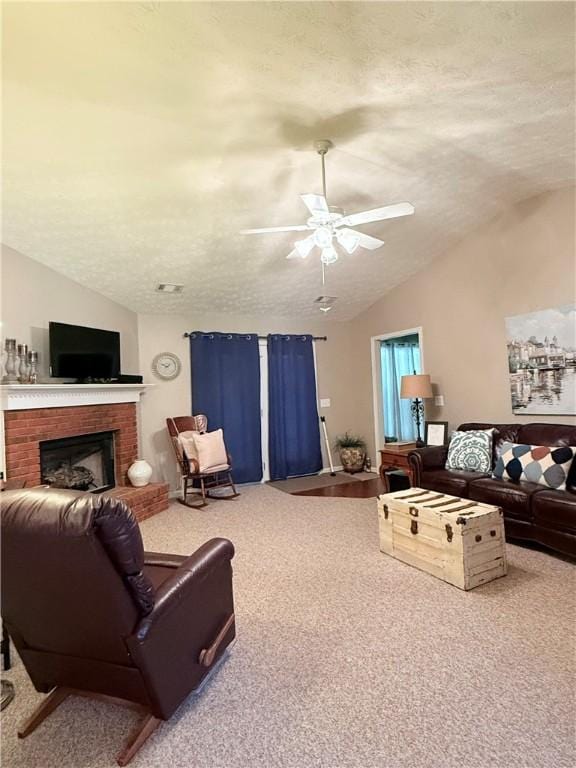 living area featuring a textured ceiling, carpet, vaulted ceiling, ceiling fan, and a brick fireplace
