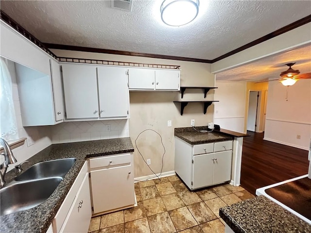 1128 Overwood Pl, Auburn, AL 36830 - kitchen featuring ceiling fan, dark countertops, a textured ceiling, white cabinetry, and ornamental molding