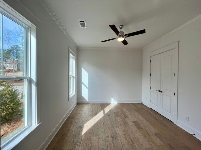 empty room featuring hardwood / wood-style flooring, ornamental molding, and ceiling fan