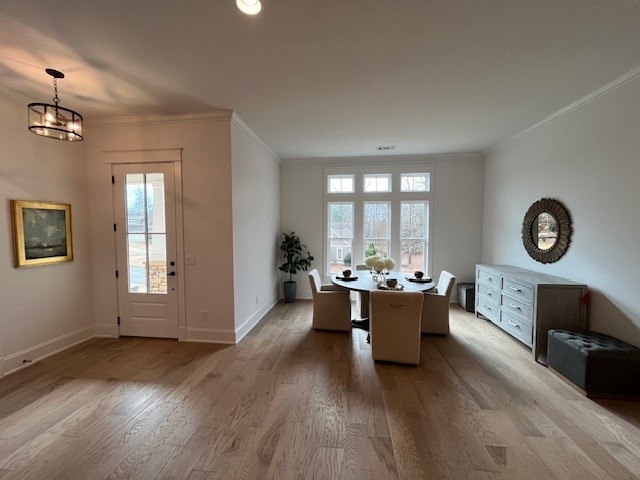 unfurnished dining area featuring ornamental molding, light hardwood / wood-style floors, and a chandelier