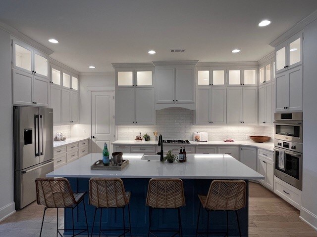 kitchen featuring a kitchen island with sink, white cabinetry, and stainless steel appliances