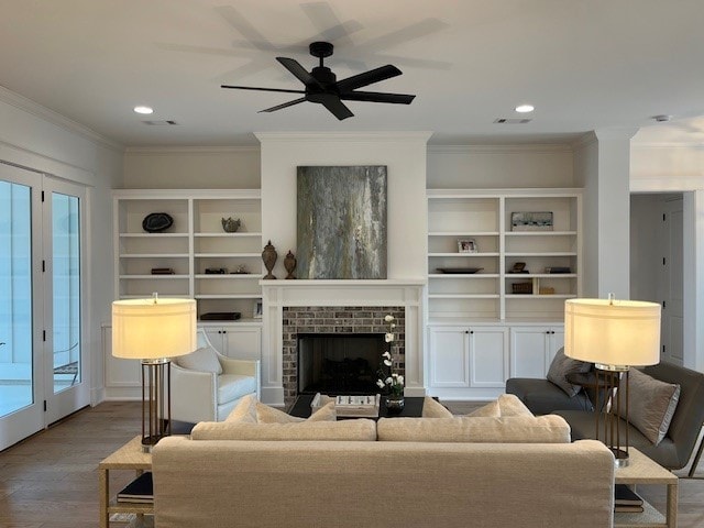 living room featuring hardwood / wood-style flooring, ceiling fan, a fireplace, ornamental molding, and a healthy amount of sunlight