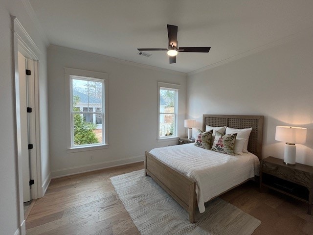 bedroom featuring ornamental molding, light hardwood / wood-style floors, and ceiling fan