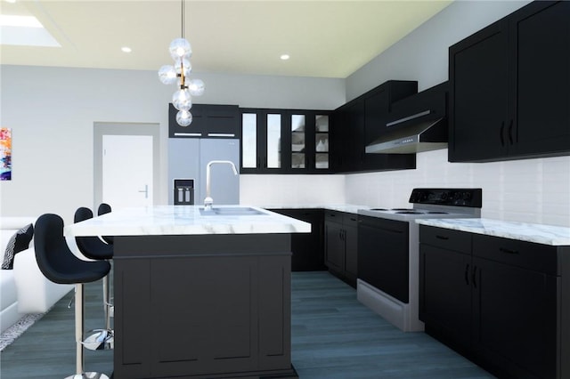 kitchen featuring electric range, sink, tasteful backsplash, a kitchen bar, and a kitchen island with sink