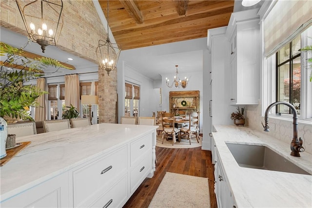 kitchen with an inviting chandelier, a sink, dark wood finished floors, wood ceiling, and light stone counters