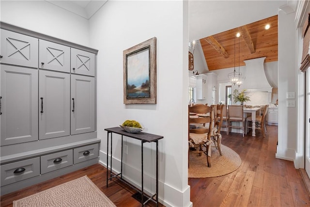 interior space with wooden ceiling, baseboards, a chandelier, dark wood-type flooring, and vaulted ceiling with beams