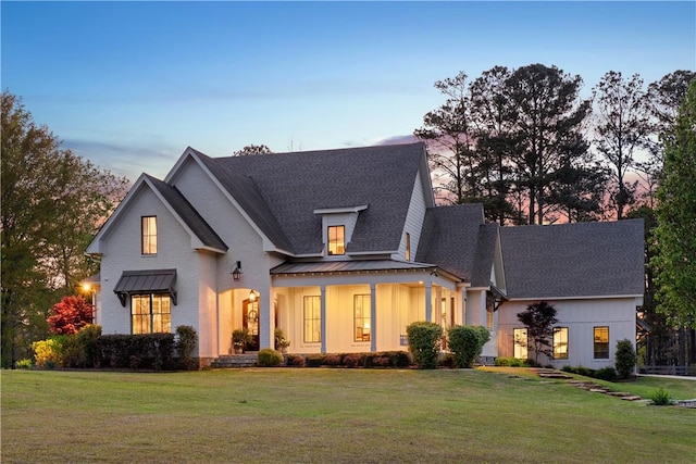 view of front of property with a shingled roof, a standing seam roof, a front lawn, and metal roof