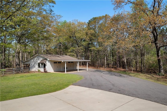 view of front of property featuring a front yard, aphalt driveway, a view of trees, fence, and an attached carport