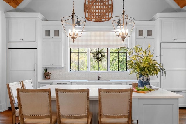kitchen featuring a center island, paneled refrigerator, a sink, and glass insert cabinets