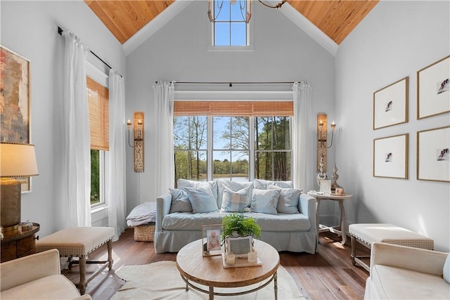 living area with high vaulted ceiling, wooden ceiling, a chandelier, and wood finished floors