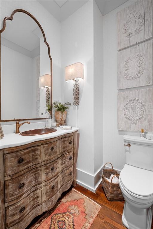 bathroom with toilet, baseboards, vanity, and wood finished floors