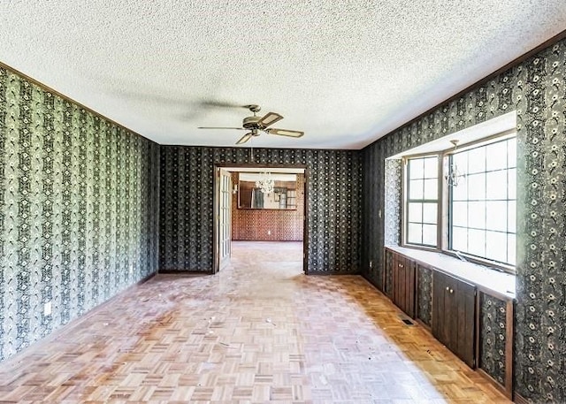 spare room with ceiling fan, a textured ceiling, and light parquet floors