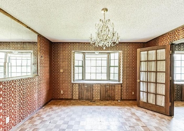 unfurnished dining area with french doors and a notable chandelier