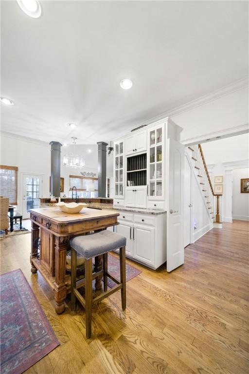 1540 Lakewood Pl, Auburn, AL 36801 - kitchen with light wood-type flooring, white cabinets, crown molding, and ornate columns