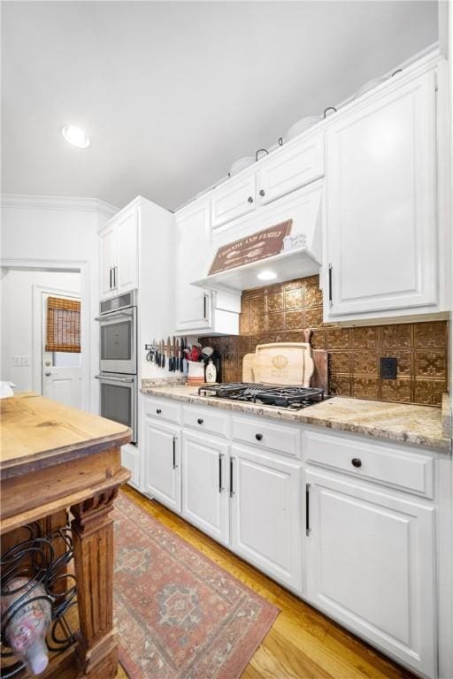 1540 Lakewood Pl, Auburn, AL 36801 - kitchen featuring light wood-style flooring, custom range hood, stainless steel appliances, backsplash, and white cabinets