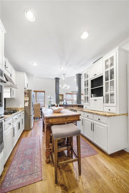 1540 Lakewood Pl, Auburn, AL 36801 - kitchen with decorative columns, stainless steel appliances, light wood-style floors, white cabinets, and glass insert cabinets