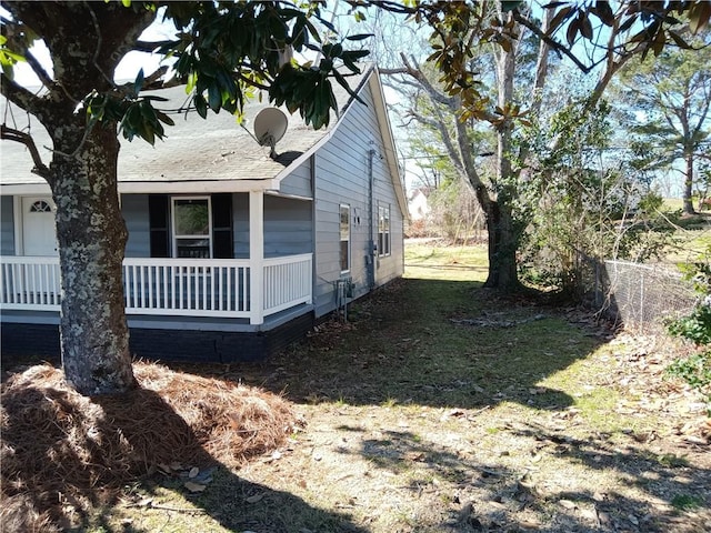 view of side of home featuring fence, a porch, and a lawn