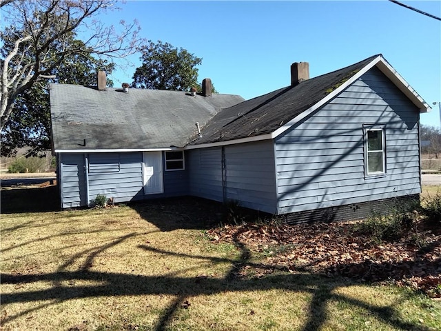 back of property with a chimney and a lawn