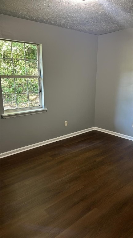 spare room with dark wood-type flooring and a textured ceiling