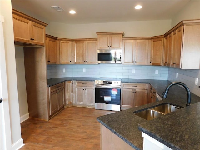 kitchen with sink, stainless steel appliances, tasteful backsplash, kitchen peninsula, and light wood-type flooring