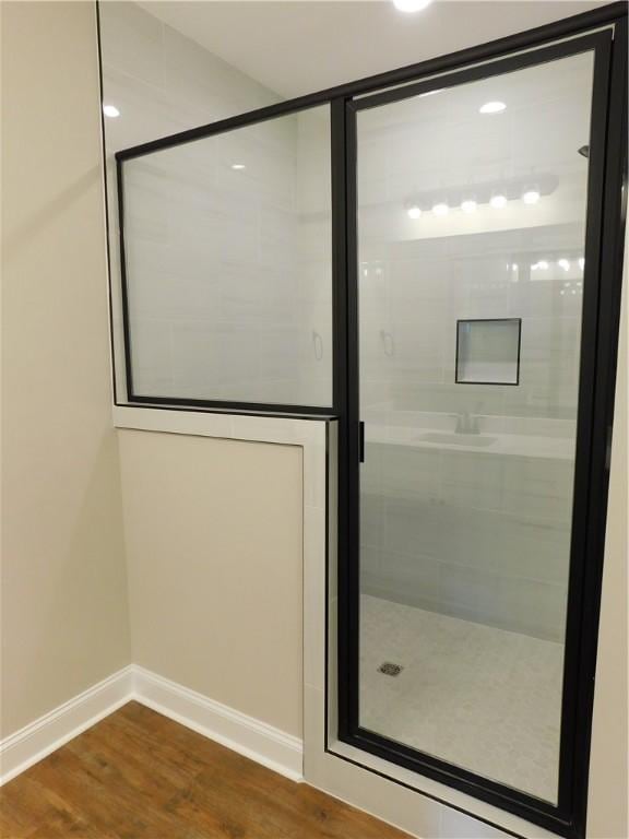 bathroom with hardwood / wood-style flooring and an enclosed shower