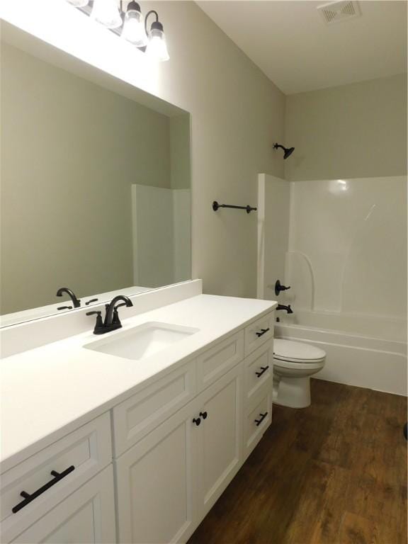 full bathroom with wood-type flooring, toilet, vanity, and  shower combination