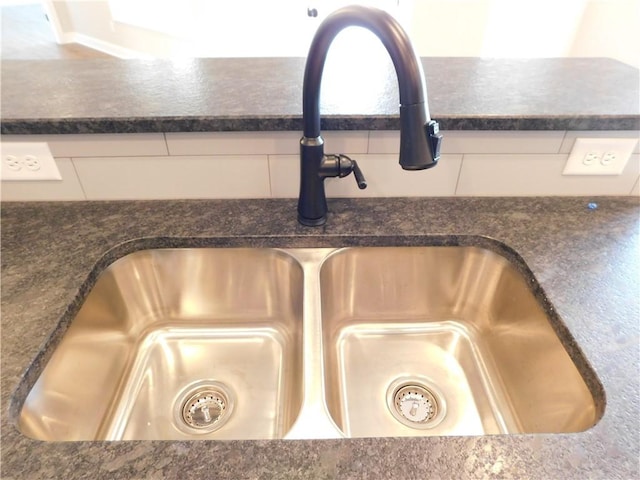 room details featuring white cabinetry, sink, and dark stone countertops