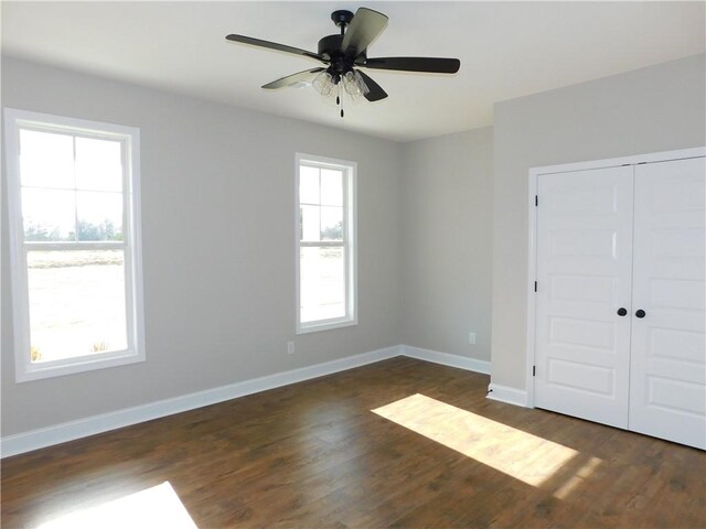 unfurnished bedroom featuring dark wood-type flooring, a closet, and ceiling fan