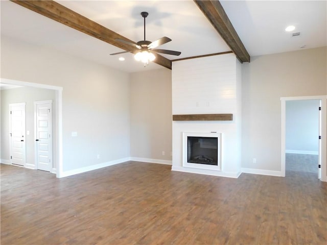 unfurnished living room with beamed ceiling, ceiling fan, a large fireplace, and dark hardwood / wood-style floors