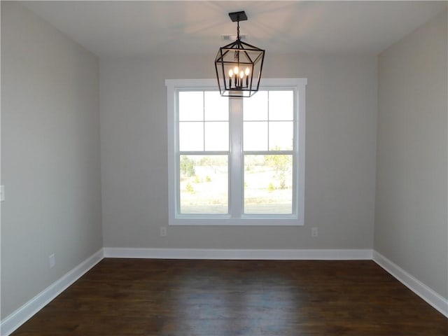 empty room with dark hardwood / wood-style flooring and a chandelier