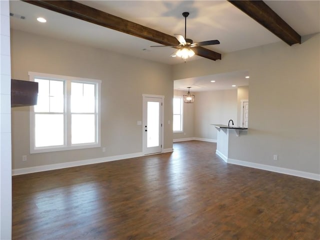 unfurnished living room featuring beam ceiling, dark wood-type flooring, and ceiling fan