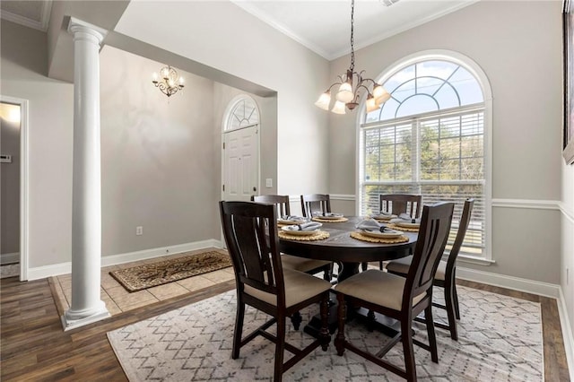 dining space with a healthy amount of sunlight, a notable chandelier, decorative columns, and wood finished floors