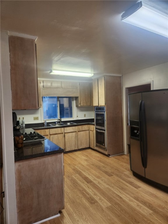 kitchen featuring kitchen peninsula, stainless steel fridge, double wall oven, sink, and light hardwood / wood-style floors