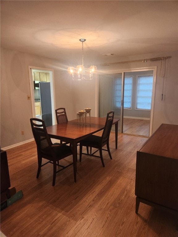 dining space with wood-type flooring and an inviting chandelier