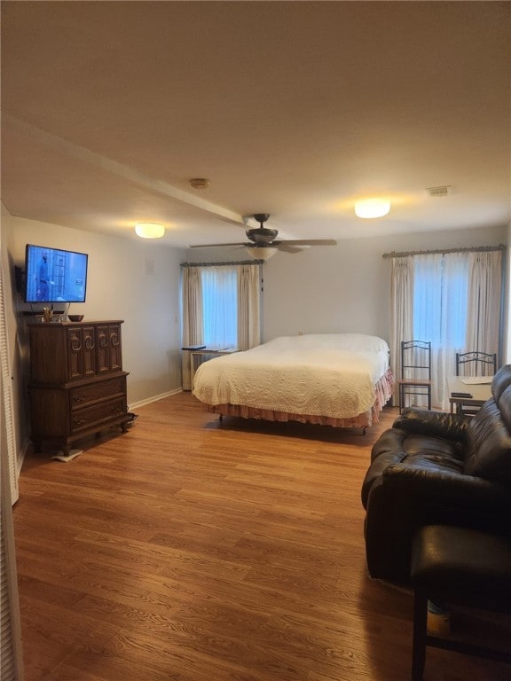 bedroom with hardwood / wood-style flooring, ceiling fan, and multiple windows