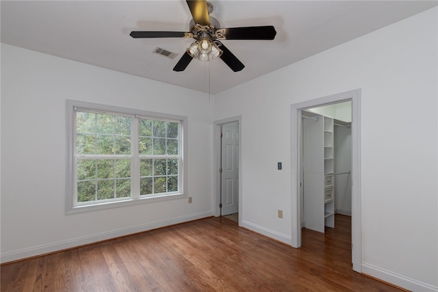 unfurnished bedroom with ceiling fan, dark hardwood / wood-style flooring, a spacious closet, and a closet