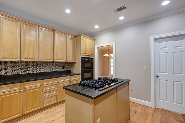 kitchen with a center island, dark stone counters, black appliances, ornamental molding, and a chandelier