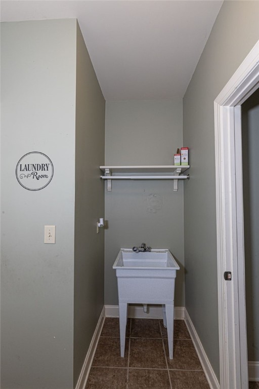 clothes washing area with sink and dark tile patterned flooring