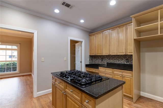 kitchen featuring a center island, dark stone counters, black gas stovetop, crown molding, and light hardwood / wood-style floors